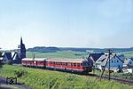 Vorbei an der kath. Kirche von Nistertal rollen 517 003 und 817 603 in Enspel dem nächsten Halt in Erbach entgegen. (30.07.1981) <i>Foto: Joachim Bügel</i>