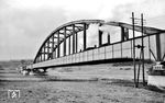 Ein unbekannter Dampfzug passiert die Weserbrücke zwischen Holzminden und Höxter an der Bahnstrecke Kreiensen—Altenbeken. Die Brücke, die zwischen 1863 und 1865 entstand, wurde vom Bauingenieur Johann Wilhelm Schwedler entworfen und von der Firma Jacobi, Haniel & Huyssen, auch bekannt unter dem Namen Gutehoffnungshütte, in Oberhausen-Sterkrade ausgeführt. Kurz vor Ende des Zweiten Weltkriegs wurde die Brücke zusammen mit der Stadtbrücke von Höxter von deutschen Truppen am 7. April 1945 völlig sinnlos auf ihrem Rückzug gesprengt.  (1937) <i>Foto: Theo Felten</i>