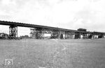 Gegen Ende des Zweiten Weltkriegs wurde die Rheinbrücke nördlich von Worms am 20. März 1945 durch die Deutsche Wehrmacht gesprengt. Dabei wurden die Stromüberbauten und zwei Flutbrücken zerstört. 1946 begann auf Anweisung der französischen Militärregierung der Bau einer Behelfsbrücke. Sie entstand parallel und 26 m stromaufwärts zur Ruine der alten Brücke und wurde als kombinierte eingleisige Eisenbahn- und Straßenbrücke errichtet. Dieses Verschwenken der Brückenachse erforderte zu den bestehenden Brückenrampen Ausschwenkungen im Bauwerk selbst, für das auch neue Strompfeiler errichtet werden mussten. Am 15. Oktober 1948 erfolgte die Inbetriebnahme des Bauwerkes. Die Bedeutung dieses Provisoriums für den Eisenbahnverkehr war nur gering, da die Brücke tagsüber meist dem Straßenverkehr zur Verfügung stehen musste. Das Bild zeigt eine erste Belastungsprobe der provisorischen Brücke durch eine Lok der Baureihe 50 Ük oder 52 im Juni 1948. (06.1948) <i>Foto: RBD Mainz, Slg. W. Löckel</i>