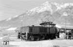 E 60 12 (Bw Garmisch-Partenkirchen) als Rangierlok in ihrem Heimat-Bahnhof. Wie alle anderen E 60 war sie 1958/59 im AW München-Freimann umgebaut worden. Dabei erhielt das Führerhaus auf jeder Seite zwei und an den Stirnseiten ein zusätzliches Fenster, die nun gummigefasst waren. An den Stirnseiten wurden Rangiererbühnen angebaut, und die großen Kühlschlangen an der Seite durch kleinere ersetzt. Die Stromzuführung vom Dachstromabnehmer zum Motorraum war nun außermittig angebracht und hatte eine geschwungene Form. Außerdem wurde die elektrische Ausrüstung erneuert. Der ursprünglich grüne Anstrich wurde durch einen purpurroten ersetzt.  (12.1962) <i>Foto: Hermann Gerdes</i>