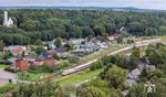 ICE 1076 aus Berlin fährt in den Bahnhof Lietzow auf Rügen ein. Dort wartet ein Triebzug der ODEG die Kreuzung ab. Links ist die Villa „Schloss Lichtenstein“ zu sehen, die nach dem Vorbild des Schlosses Lichtenstein bei Reutlingen auf der Schwäbischen Alb erbaut wurde. (25.08.2024) <i>Foto: Joachim Schmidt</i>