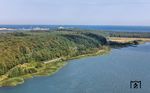 101 102 schiebt den IC 2261 nach Rostock vorbei am Kleinen Jasmunder Bodden in Richtung Lietzow. Im Hintergrund sind die Fähranlagen von Sassnitz/Mukran zu erkennen. (26.08.2024) <i>Foto: Joachim Schmidt</i>