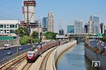 Obwohl die Eisenbahn in Israel eine mehr als 130 Jahre alte Tradition hat (die erste Eisenbahnstrecke wurde 1892 zwischen Jaffa und Jerusalem eröffnet), war sie bis 1990 so etwas wie ein Aschenputtel. Die eher zufällige Handvoll Strecken, die nur bedingt mit der Siedlungsstruktur des neuen Staates Israel übereinstimmten, spielte die Eisenbahn in Israel lange Zeit kaum eine Rolle. So lagen – und liegen noch heute – die Bahnhöfe oft weit außerhalb der neu entstehenden Städte, die sie bedienen sollen. Neu gebaute Bahnhöfe an Neubaustrecken konnten jedoch aus Kostengründen oftmals ebenfalls nicht näher an die Stadtzentren gerückt werden. Investitionen in den Verkehrsbereich kamen bis in die 1990er Jahre ganz überwiegend der Straße zugute, denn Straßen galten im Kriegsfall, der im Land immer drohte, als zuverlässiger und besser nutzbar. Erst seit Ende der 1990er Jahre werden Bahnprojekte zur Entlastung von Straßen und Umwelt massiv vorangetrieben. Ein Klassiker des 'neuen' Nahverkehrs ist gegenwärtig der aus deutschen Doppelstockwagen bestehende Wendezug zwischen Tel Aviv Merkaz und HaShalom. Rechts und links der Strecke sieht man noch deutlich, wem jahrzehntelang die Prioritäten galten. (14.09.2008) <i>Foto: Georg Fladt-Stähle</i>