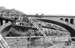 Ein Schwebebahnzug der Wuppertaler Schwebebahn mit dem Hauptwagen Nr. 14 und dem Nebenwagen Nr. 25 aus der ersten Bauserie von 1900 an der Sonnborner Brücke in Wuppertal-Elberfeld. Über die Brücke führt die Bergisch-Märkische Eisenbahn. (1950) <i>Foto: Carl Bellingrodt</i>