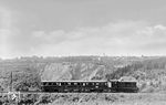 V 36 223 (Bw Wuppertal-Steinbeck) mit VS 145 064 auf dem Weg nach Wuppertal-Cronenberg in Wuppertal-Küllenhahn. Im Hintergrund ist der 1892 eröffnete Grauwackesteinbruch Korzert zu sehen, der im Bahnhof Küllenhahn einen eigenen Gleisanschluss besaß. Er produzierte vor allem Gleisschotter für die Reichsbahn, aber auch Körnungen für den Straßen- und Betonbau sowie Naturwerksteine. Um 1970 endete der Steinabbau und in der Bruchsohle bildete sich ein See, der sogenannte „Silbersee“. Auf der Höhe am Bruchrand begann 1972 der Bau eines Müllheizkraftwerks für die Stadt Wuppertal. An den Steinbruchbetrieb wie auch an die Eisenbahntrasse erinnert heute nichts mehr. Sie wurde 2007 zu einem Radweg umgebaut. (18.05.1950) <i>Foto: Carl Bellingrodt</i>