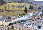 99 1734 dampft durch Schmiedeberg. Der Viadukt ist mit 191 Metern Gesamtlänge das längste Brückenbauwerk entlang der Weißeritztalbahn. Die Brücke wurde erst 1920 im Rahmen der Neutrassierung des Abschnittes Obercarsdorf–Buschmühle über die Einmündung des Pöbelbachtales in der Ortslage Schmiedeberg errichtet. Wegen der seinerzeit hohen Stahlpreise wurde anstatt der ursprünglich konzipierten Stahlträgerbrücke eine Bogenbrücke mit acht Bögen in Stahlbetonkonstruktion ausgeführt. Aus optischen Gründen erhielt die Brücke eine Natursteinverkleidung.  (07.01.2025) <i>Foto: Joachim Schmidt</i>