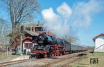 Ausfahrt der 03 2155 aus dem bahnhof Neustadt (Orla). Das zwei- bis dreistöckige Bahnhofsgebäude wurde um 1875 in Klinkerbauweise fertiggestellt. Bis in die 2000er Jahre wurden im Erdgeschoss des Hauses Fahrkarten verkauft, dann wurde der Schalter mitsamt der Wartehalle stillgelegt. Auch die Bahnhofsgaststätte wird seit mehreren Jahrzehnten nicht mehr betrieben. Nach zahlreichen Rückbauten existieren im Bahnhof nur noch das durchgehende Hauptgleis 2 und das Gleis 1 am Hausbahnsteig. Als Folge des Abbaues des zweiten Streckengleises zwischen Triptis und Oppurg nach dem Zweiten Weltkrieg ist Gleis 1 nur mit 60 km/h über zwei Weichen in die heutigen eingleisigen Strekenabschnitte befahrbar. Fast alle haltenden Züge verkehren daher über das Gleis 2. (03.04.2025) <i>Foto: Atijana Schmidt</i>