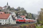 218 424 fährt mit RE 4854 nach München in Nabburg mit der alles überragenden gotischen Stadtpfarrkirche St. Johannes Baptist ein. Das Vorsignal gehört zum Ausfahrsignal des Bahnhofs. (14.04.2025) <i>Foto: Joachim Bügel</i>