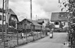 E 32 12 (Maffei, Baujahr 1924) fährt mit einem Personenzug von Zell (Wiesental) nach Basel Bad Bf in den Bahnhof Riehen ein. Der Bahnübergang an der Schmiedgasse existiert heute noch, der Rollerfahrer ist im Eisenbahnweg unterwegs. (07.1958) <i>Foto: Jürgen Hagemann, Slg. R. Garn</i>