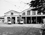 Blick in den Betriebshof Süd im Stadtteil Wiehre, der von 1901 bis 1994 eines von zwei Depots der Freiburger Straßenbahn war. Er lag an der Urachstraße, unweit der Haltestelle Lorettostraße. Die Errichtung dieses Depots war nicht im Bauauftrag für die Straßenbahn enthalten, sondern wurde vom städtischen Hochbauamt übernommen. Die Jugendstilgebäude wurden 1907/1908 um ein Hinterhaus und einen Zwischenbau erweitert. Zudem wurde die Wagenhalle, die anfangs für 35 Fahrzeuge ausgelegt war, zeitgleich um eine weitere Abstellhalle ergänzt, sodass nach diesem Umbau 77 Fahrzeuge stationiert werden konnten. Mit dem Anschluss des neuen Betriebshofs West an das Schienennetz 1994 verlor das Depot seine Bedeutung. Heute sind im westlichen und älteren Teil des Depots die historischen Fahrzeuge der Freunde der Freiburger Straßenbahn untergebracht, die östliche Halle dient der Feuerwehr.  (05.1967) <i>Foto: Reinhard Todt</i>