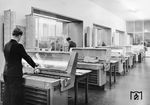 Blick in eine Fahrkartenausgabe mit den damals modernen AEG-Fahrkartendruckern. An den etwa 6500 Fahrkarten-Schaltern der DB wurden Mitte der 1950er Jahre mehr als 460 Millionen Fahrausweise ausgegeben. In den 760 Fahrkartenausgaben, die bereits mit einem modernen AEG-Fahrkartendrucker ausgestattet waren, wurden allein 137 Millionen Karten gedruckt. Die AEG-Großdrucker benötigten für den Druck einer Fahrkarte mit Rechen- und Kontrollfunktion weniger als eine Sekunde. Damit wurde die Abfertigung am Schalter wesentlich beschleunigt. (1959) <i>Foto: BD Mainz</i>