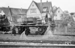 Unkrautbekämpfung auf dem "Öchsle" mit dem auf dem Schienentransportwagen "Stuttgart 1100" des Gleislagers Heilbronn aufgebockten "Bahnhofsspritzgerät Nr. 1" im Bahnhof Ochsenhausen. Das Foto zeigt sehr schön die alte Eisenbahn, wo ohne Zeitdruck die notwendige Arbeit gewissenhaft erledigt werden konnte. Mit dem Lokpersonal sind 5 Mann mit der Unkrautbeseitigung beschäftigt, heute in Zeiten von Personalmangel undenkbar. Schutzmaßnahmen für die Bediensteten waren nicht erforderlich, weil das damals verwendete Unkraut-Ex als Wirkstoff das Salz "Natriumchlorat" enthielt, bezüglich Schädlichkeit ist es etwa mit Natriumchlorid (Kochsalz) vergleichbar. Erst mit den Unkrautvernichtungsmittel auf Glyphosat-Basis war man gut beraten, jeden Hautkontakt zu vermeiden, da Glyphosat Krebserkrankungen hervorrufen kann.  (26.04.1960) <i>Foto: Gerhard Karl</i>