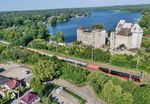 01 0509 fährt mit DPE 1820 von Leipzig nach Putbus am Röblinsee in Fürstenberg (Havel) vorbei. Der große Gebäudekomplex war das ehemalige VEB Kraftfuttermischwerk (KFM), ex Behrnsche Mühle. (14.06.2025) <i>Foto: Joachim Schmidt</i>