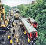 Unweit des Bahnhofs Großkönigsdorf (im Hintergrund) entgleiste die Zuglok 110 477 des D 225 sowie drei Wagen des Zuges. Bei dem Aufprall auf die Straßenüberführung "Augustinusstraße" wurde die Lok herumgerissen und landete auf dem Nachbargleis. Da sich die Kupplung des ersten Wagens nicht von der Lok löste, verbog sich dieser in der Mitte, sodass das Vorder- und Hinterteil fast parallel zueinander zum Stehen kamen. Alleine in diesem Wagen starben 5 Menschen. Das Bild zeigt den Zustand einen Tag nach dem Unfall, besagter Wagen (rechts außen) wurde teilweise wieder gerichtet und mit den anderen Fahrzeugen hinter der Unfallbrücke abgelegt.  (27.05.1983) <i>Foto: Joachim Schmidt</i>