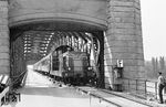 SNCF BB 66045 mit dem von der Kehler Strecke umgeleiteten D 40 "Mozart" (Wien West - Strasbourg) auf der Rheinbrücke Wintersdorf. Die von den Deutschen im Dezember 1944 gesprengte Brücke wurde Ende 1947 auf Veranlassung der französischen Militärregierung wiederaufgebaut, um einen weiteren Rheinübergang für ihre Nachschubstrecken nutzen zu können. Im Mai 1949 ging sie in Betrieb. Am 7. Oktober 1950 wurde der Reisezugverkehr zwischen Rastatt und Wintersdorf (Baden) eingestellt. Die gesamte Bahnstrecke wurde nur noch eingleisig als Nebenbahn betrieben. Ab 1954 erfolgte die Finanzierung des Unterhalts des deutschen Teils der Rheinbrücke aufgrund strategischer Interessen der NATO durch das Bundesministerium der Verteidigung. Seit Anfang 1998 hat die NATO kein Interesse mehr an der Bahnstrecke und der Rheinbrücke. Der Unterhalt obliegt seitdem der Straßenbauverwaltung Baden-Württembergs. Eine erneute Nutzung als Eisenbahnbrücke beispielsweise im Rahmen der deutsch-französischen Schnellverkehr-Verbindungen wurde diskutiert; allein aufgrund des Bauzustandes der bereichsweise über 100 Jahre alten Brücke ist die Zukunft des Bauwerkes ungewiss. (16.05.1966) <i>Foto: Wolfgang Jahn</i>