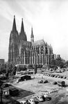 Die Folgen des Zweiten Weltkriegs bescherten diesen freien Blick auf den Kölner Dom. Heute ist die freie Fläche durch das Museum Ludwig zugebaut. Rechts befindet sich der Kölner Hauptbahnhof. Der Kölner Dom ist eine der größten Kathedralen im gotischen Baustil. Sein Bau wurde 1248 begonnen und nach 632 Jahren (!) im Jahr 1880 vollendet. Tatsächlich war der vollendete Dom nur wenige Jahre ohne Gerüst zu sehen. Nach der offiziellen Domvollendung 1880 wurden noch rund 20 Jahre Nacharbeiten durchgeführt, die gefühlt bis heute nicht geendet haben. Der Grund ist die aus verschiedenen Gesteinen errichtete Fassade, die aufgrund ihrer Eigenschaften unterschiedlich stark verwittert und einer kontinuierlichen Erneuerung bedarf. (1955) <i>Foto: Fischer</i>