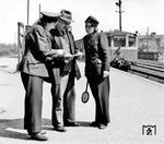 Auf dem Berliner S-Bahnhof Pankow-Heinersdorf geben zwei bei der Reichsbahn bedienstete Frauen einem Fahrgast Auskunft. Im Hintergrund fährt ein S-Bahnzug der Bauart "Stadtbahn" (ET/ES/EB 165) ein. (1942) <i>Foto: RVM (Ittenbach)</i>