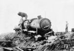 Lt. dem Original-Bildtext schaut sich ein amerikanischer Soldat eine zerstörte deutsche Lokomotive an. Dabei handelt es sich um 50 3094 ÜK vom Bw Saargemünd, die zwischen Saaralben und Saargemünd bei einem US-Luftangriff getroffen wurde. Die im August 1943 in Dienst gestellte Lok unterstand nach dem Krieg der luxemburgischen Administration des Domaines und wurde am 15.11.1947 dem Bw Koblenz-Mosel zugewiesen. Ab 23. September 1947 wurde sie als 1-150-Z-3094 in den Bestandslisten der Betriebsvereinigung der Südwestdeutschen Eisenbahnen (SWDE) – Association pour l'Exploitation des Chemins de Fer de Sud-Ouest de l'Allemagne – in den Ländern der französischen Besatzungszone geführt. Am 14.11.1953 wurde sie in Hagenau (Haguenau) ausgemustert. (03.1945) <i>Foto: Pressefoto ACME</i>