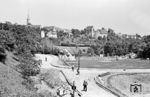 Eine 93er mit einem Personenzug Richtung Leonberg vor der Ortskulisse von Höfingen. Im Vordergrund wird gerade die Straßenkreuzung Am Schlossberg/Lindenberg erneuert. Der Fußballplatz mit dem dahinterliegenden Freibad an der Glems existiert heute noch. (07.1959) <i>Foto: Jürgen Hagemann, Slg. R. Garn</i>