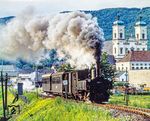 Direkt in der Bahnhofsausfahrt aus Garsten passiert die Steyrtalbahn die barocke Stiftskirche, die als Kloster im Jahr 1082 gegründet worden war. Seit dem Jahr 1851 befindet sich in den Gebäuden des ehemaligen Stifts eine Strafvollzugsanstalt. Die ehemalige Stiftskirche dient als Pfarrkirche. 298.51 dampft mit dem morgendlichen P 3665 vorbei. (08.1980) <i>Foto: Karsten Risch</i>