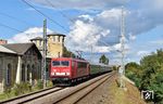 155 273 der Traditionsgemeinschaft Bw Halle P mit einer Leerwagenüberführung (DLr) von Wustermark nach Saalfeld (Saale) in Delitzsch ob. Bf mit dem unter Denkmalschutz stehenden Empfangsgebäude aus dem Jahr 1872 an der Hauptbahn Halle (Saale) Hbf–Guben. In Höhe des ersten Wagens verläuft unter der Brücke die Strecke Leipzig–Berlin. Westlich schließt sich der Güterbahnhof Delitzsch an, in dem bis 1967 Anschluss an das Netz der ehemaligen Delitzscher Kleinbahn bestand.  (12.09.2025) <i>Foto: Ralf Opalka</i>