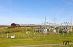 218 497 mit IC 2310 aus Köln am Umspannwerk Friedrich-Wilhelm-Lübke-Koog westlich von Klanxbüll. Von hier aus versorgen 30 Windenergieanlagen mit einer Gesamtleistung von 70 Megawatt circa 100.000 Haushalte mit regenerativem Strom. In den letzten Jahren musste in der beschaulichen nordfriesischen Gemeinde jedoch immer mehr Strom aufgrund mangelnder Netzkapazitäten abgeregelt werden, um einer Überlastung der Netze vorzubeugen. So wurden 2024 deutschlandweit über 5,5 Milliarden Kilowattstunden Windstrom abgeregelt und damit nicht in das Stromnetz eingespeist. Als Lösung wird am Friedrich-Wilhelm-Lübke-Koog anhand der Kopplung von Windstrom und Wärme getestet, wie man die Überkapazitäten zum Heizen nutzen kann. (24.09.2025) <i>Foto: Joachim Bügel</i>