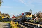 218 330 schiebt den RE 11081 nach Husum über den Bü Westerweg in der Einfahrt in den Bahnhof Klanxbüll. Wegen der Modernisierung der Strecke waren ab Klanxbüll alle Bahnübergänge bis Niebüll gesperrt. (24.09.2025) <i>Foto: Joachim Bügel</i>