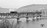 Die Moselbrücke in Bullay war zunächst als reine Eisenbahnbrücke geplant. Nachdem sich die umliegenden Gemeinden und der Landkreis sowie Unternehmer finanziell beteiligten, genehmigte die preußische Regierung 1875 den Bau einer Doppelstockbrücke für Schiene und Straße. Mit Zunahme des Transportaufkommens musste die Brücke 1928–1929 umgebaut und verstärkt werden. Die Überbauten wurden mit einem Strebenfachwerk mit Zwischenfeldern unter den Obergurten ausgeführt. Die neue Konstruktion hat eine Systemhöhe von 11 Metern und eine Stahlmasse von 2000 Tonnen. Das Bauwerk ist neben den beiden doppelstöckigen Brücken der Biggetalbahn eines von nur drei seiner Art in Deutschland. 044 953 rumpelt mit einem Güterzug nach Ehrang über die Moselbrücke. (16.10.1971) <i>Foto: Burkhard Wollny</i>
