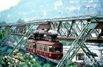 Die ständig wachsenden Fahrgastzahlen der Wuppertaler Schwebebahn, einen Rekord stellte das Jahr 1942 dar, führten in diesem Jahr zur Neubestellung einer 60 Wagen umfassenden Serie, die alle Bestandsfahrzeuge aus der Eröffnungszeit ablösen sollten. Trotz Baubeginns im Jahr 1943 verzögerte sich die Inbetriebnahme des ersten Wagens kriegsbedingt bis zum 27. November 1950. Die neuen Fahrzeuge mit den Betriebsnummern 59 bis 78 (hier die Nr. 63) verfügten über einen geschweißten statt genieteten Wagenkasten, womit sie deutlich leichter waren, drei automatische Doppel-Schiebetüren, geräuscharme Schneckengetriebe und verkleidete Drehgestelle und sie waren gefedert. Zusätzliche Pendeldämpfer und Blattfedern vermieden das Pendeln der Wagen bei Stillstand in den Stationen. Neu waren außerdem die Dreiersitzbänke, somit hatte die Baureihe 50 keinen Mittel- sondern einen Seitengang. Von den insgesamt 31 Sitzplätzen gehörten dabei zehn zur teureren 1. Klasse (!) im hinteren Drittel des Wagens, abgetrennt durch eine verglaste Zwischenwand mit Schiebetür und eigener Zugangstür vom Bahnsteig aus. Auch an die Fahrer war gedacht worden, sie konnten erstmals ihre Tätigkeit sitzend ausüben. (1968) <i>Foto: Andrew Walker</i>