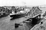 Die britische "CHAPMAN" fährt auf dem Nord-Ostsee-Kanal durch die geöffnete Drehbrücke in Rendsburg. Im Hintergrund ist die zwischen 1911 und 1913 erbaute Hochbrücke zu sehen, über die die Bahnstrecke Neumünster–Flensburg führt. (1955) <i>Foto: Slg. Thorsten Eichhorn</i>