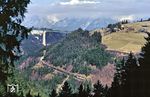 Blick von Schönberg im Stubaital auf eine DB-140 und 111, die mit dem Ex 281 "Alpen-Express" von München nach Roma Termini auf der Brennerbahn bei Patsch unterwegs sind. Im Hintergrund ist die Europabrücke der Brenner Autobahn A 13 zu sehen. Mit einer Höhe von 190 m über Grund war sie zum Zeitpunkt ihrer Fertigstellung 1963 für rund 10 Jahre die höchste Brücke Europas. Ihr höchster Pfeiler war mit einer Höhe von 146,5 m der höchste Brückenpfeiler der Welt. Sie ist nach wie vor die höchste Brücke Österreichs.  (21.02.1988) <i>Foto: Joachim Bügel</i>