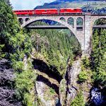 Lok 627 "Reichenau-Tamins" auf dem Soliser-Viadukt. Die den Fluss Albula überspannende Brücke ist 85 m hoch und 164 m lang. Sie besteht aus einem Hauptbogen mit einer Spannweite von 42 m und zehn Nebenbögen von 8 bis 10 m. Sie ist nach dem Wiesener Viadukt die zweithöchste Brücke der RhB und nach dem Sitterviadukt die dritthöchste Eisenbahnbrücke der Schweiz. Dahinter ist die Straßenbrücke von 1972 mit einer Weite von 72 m zu sehen. (06.1989) <i>Foto: Karsten Risch</i>