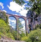 Ein Güterzug in Richtung Filisur mit einer Ge 6/6 ("Krokodil") auf dem Landwasserviadukt. Die Bahntrasse weist im Bereich des Viaduktes eine Steigung von 20 Promille und einen Kreisbogen mit einem Radius von 100 Metern auf. Das Landwasser wird mit sechs 20 Meter weit spannenden Gewölben überbrückt, die auf fünf hohen Pfeilern ruhen. Das südöstliche Widerlager der Brücke liegt mitten in einer hohen Felswand, und die Gleise führen direkt in den 216 m langen Landwassertunnel. Das Mauerwerk umfasst rund 9200 Kubikmeter und ist mit Kalkdolomit verkleidet.  (05.1987) <i>Foto: Karsten Risch</i>