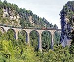 Eine Ge 6/6 II mit dem 'Glacier-Express' auf dem Landwasserviadukt. Der 'Glacier Express' wird oft als der "langsamste Schnellzug der Welt" bezeichnet. In ungefähr acht Stunden fährt der Zug über 291 Brücken, durch 91 Tunnel und über den 2033 m hohen Oberalppass nahe der Rheinquelle. Der Zug verbindet seit 1930 den Engadiner Ort St. Moritz über Chur, Disentis/Mustér, Andermatt, Brig und Visp mit Zermatt auf durchgehend meterspuriger Strecke. Dabei durchquert er die Kantone Graubünden, Uri und Wallis.  (09.1981) <i>Foto: Karsten Risch</i>
