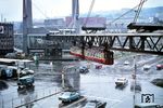 Ein Schwebebahnzug überquert bei typisch Wuppertaler Wetter die neue Straßenkreuzung am 'Alten Markt'. Vier 38 Meter hohe Pylonen halten hier das Gerüst der Schwebebahn auf einer Strecke von 120 Metern über der Kreuzung. (06.1970) <i>Foto: Jürgen Hagemann</i>