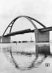 Ein Schnellzug mit einer V 200.1 auf der am 30. April 1963 eingeweihten Fehmarnsundbrücke. Die kombinierte Straßen- und Eisenbahnbrücke überspannt den ca. 1300 m breiten Fehmarnsund. Die Fehmarnsundbrücke hat für den Schiffsverkehr eine lichte Öffnung von 240 m Breite und 23 m Höhe über dem Mittelwasser. Nach Eröffnung der Brücke konnte die Eisenbahnfähre Großenbrode–Gedser (Streckenlänge ca. 60 km) eingestellt und durch die mit 18,6 km deutlich kürzere Fährverbindung zwischen Puttgarden und Rødbyhavn ersetzt werden. Das Landesamt für Denkmalpflege Schleswig-Holstein stellte die Fehmarnsundbrücke 1999 unter Denkmalschutz. (09.08.1963) <i>Foto: Reinhold Palm</i>
