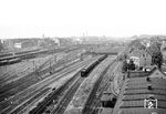 Der Bahnhof Düsseldorf-Derendorf liegt etwa vier Kilometer nördlich des Hauptbahnhofs. Der hier zu sehende Rangierbahnhof erstreckte sich noch weiter südlich bis in den Stadtteil Pempelfort, wo seine bis 1877 zurückreichenden Wurzeln als Bahnhof 'Düsseldorf Rheinisch' der Rheinischen Eisenbahn-Gesellschaft liegen. Der Bahnhof war auch Ausgangspunkt der Rheinischen Strecke über Wuppertal nach Dortmund, die am 15. September 1879 eröffnet wurde und häufig auch 'Wuppertaler Nordbahn' bezeichnet wird. Auf der von der Cöln-Mindener Eisenbahn-Gesellschaft (CME) 1846 eröffneten Stammstrecke von Köln-Deutz nach Minden ist ein Personenzug in Richtung Duisburg unterwegs. In den 1990er Jahren wurde der hier zu sehende südliche Bahnhofsteil des Rangierbahnhofs stillgelegt und die zugehörigen Stellwerke einschließlich Güterabfertigung abgerissen. Die zurückgebauten Gleisanlagen wurden mit Bürogebäuden überbaut.  (07.1955) <i>Foto: Ernst Winter</i>