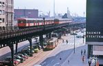 Begegnung zwischen zwei U-Bahnen der Linie U 3 und Straßenbahn-Tw 3584 (LHB, Baujahr 1951) an der Kreuzung Rödingsmarkt/Baumwall. Im Hintergrund sind Schiffe auf der Elbe zwischen den Landungsbrücken und der heutigen Elbphilharmonie zu sehen. (08.1971) <i>Foto: Jürgen Hagemann</i>