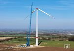 Weil die Rotorblätter wie Segel wirken und leichtester Wind die Last am Kran zum Schwingen bringen kann, ist zur Montage Windstille erforderlich, um weder die Monteure, das Rotorblatt oder auch den Kran zu gefährden. Bei Anröchte wird mit einem 185 m hohem Kran der neue Windpark „Reuterberg“ errichtet. Bei einem Rotorgesamtdurchmesser von ca. 175 Metern haben die drei Rotorblätter eine Länge von je 85 Metern. (03.03.2026) <i>Foto: Joachim Schmidt</i>