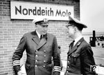 Was zunächst wie ein ungewöhnliches Treffen aussieht, war in Norddeich Mole praktizierter Alltag. Der Aufsichtsbeamte der DB spricht sich mit einem Kapitän eines Seebäderdampfers über Anschlüsse zwischen Bahn und Schiff ab. Damit sollten verpasste Fähren nach Norderney/Juist und gestrandete Urlauber vermieden werden. (1958) <i>Foto: Quebe</i>
