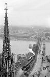 Blick vom Kölner Dom auf die Ostausfahrt des Kölner Hauptbahnhofs mit der damals noch zweigleisigen Hohenzollernbrücke über den Rhein. Wie man sieht, ist auch der Kölner Dom im Krieg nicht ganz ungeschoren davongekommen. (10.1956) <i>Foto: Ernst Winter</i>