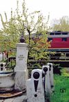 Eine 132 passiert den historischen Dorfbrunnen aus dem Jahr 1859 in Dorndorf-Steudnitz in der Einfahrt zum Bahnhof Dornburg (Saale). Der Brunnen war früher eine wichtige Wasserquelle in der Region und dient bis heute als Wahrzeichen des lokalen Kulturerbes und des Gemeindelebens. (29.04.1991) <i>Foto: Joachim Bügel</i>