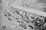 Blick auf den Bahnhof Cochem, in dem gerade zwei P 8 mit Personenzügen unterwegs sind. Links ist das 1901 errichtete Bahnbetriebswerk zu sehen, das zwischen dem Personenbahnhof und den Weinbergen in einer sehr beengten Lage stand. Es verfügte über zwei Halbrundschuppen mit einer 16-m-Drehscheibe (Schuppen mit 9 Ständen) und einer 20-m-Drehscheibe (Schuppen mit 14 Ständen). Ab 1965 war das Bw Cochem nur noch Einsatzstelle des Bw Ehrang, 1980 wurde die gesamte Anlage abgetragen. (07.1957) <i>Foto: Ernst Winter</i>