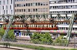 Am 24. Oktober 1900 fuhr Kaiser Wilhelm II. noch vor der am 1. März 1901 erfolgten offiziellen Eröffnung des ersten Abschnitts der Schwebebahn mit einem Sonderwagen von Elberfeld nach Vohwinkel. Der Kaiser war damals im Wagen 4 unterwegs. Der heute als 'Kaiserwagen' erhaltene Wagen 5 diente an dem Tag der Beförderung von Honoratioren kommunaler Behörden. Man entschied sich 1974 für den Erhalt des Wagens 5, da der Wagen 4 durch Änderung des Wagenkastens viel von seinem ursprünglichen Aussehen verloren hatte. 2019 wurde die Stromspannung auf der Schwebebahnstrecke von 600 V auf 750 V angehoben und zudem die Signaltechnik auf ECTS umgestellt. Für den Weiterbetrieb musste der historische Zug entsprechend angepasst werden. Im Rahmen der Arbeiten wurde festgestellt, dass die Drehgestelle und Räder wegen Anrissen erneuert werden mussten. Die Arbeiten konnten nach acht Jahren erfolgreich abgeschlossen werden. Um die neue Technik zu testen, erfolgten seit Anfang 2026 Probefahrten während der nächtlichen Betriebspausen. Mitte April wurden auch tagsüber während des Planbetriebs Probefahrten durchgeführt, wie hier nahe der Haltestelle Döppersberg in Wuppertal-Elberfeld. Nach seiner Bewährung steht der 'Kaiserwagen' nun wieder für Sonderfahrten zur Verfügung.  (24.04.2026) <i>Foto: Zeno Pillmann</i>