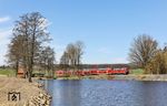 Durch den vorausfahrenden langsamen Holzzug musste 218 433 mit RE 4856 nach Hof im Bahnhof Reuth (b Erbendorf) warten und kam mit gut zehnminütiger Verspätung am Rechenweiher bei Escheldorf angebrummt. (09.04.2026) <i>Foto: Joachim Bügel</i>