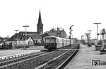 Eine sechsteilige 798/998-Einheit verlässt den Bahnhof Neumünster nach Bad Oldesloe. Im Hintergrund fährt eine 218 mit einem Güterzug in Richtung Rendsburg ein. Links ist die katholische Pfarrkirche St. Vicelin zu sehen. (1985) <i>Foto: Thorsten Eichhorn</i>