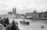 Blick über die Elbe auf den Magdeburger Dom, dem Wahrzeichen der Stadt. Ein britischer Luftangriff auf Magdeburg am 16. Januar 1945 zerstörte etwa 90 % der Altstadt, darunter 15 Kirchen. Noch 1956 war man mit der Beseitigung der Schäden beschäftigt. Das große Gebäude am Elbufer ist die Reichsbahndirektion Magdeburg, die am 18. August 1945 auf Anweisung der sowjetischen Militärverwaltung errichtet wurde. Bis 1931 bestand in Magdeburg bereits eine Reichsbahndirektion der Deutschen Reichsbahn-Gesellschaft, deren Strecken dann an die Reichsbahndirektionen Halle (Saale), Altona, Berlin und Hannover übergingen. Die (neue) Rbd Magdeburg wurde am 15. Oktober 1990 aufgelöst, der Direktionsbereich der Reichsbahndirektion Halle (Saale) unterstellt. Über dem Gebäude schauen die Türme der Klosterkirche St. Marien hervor. (07.1956) <i>Foto: Jürgen Hagemann</i>