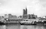 Ein Straßenbahnzug vor der zerstörten St.-Johannis-Kirche in der Magdeburger Altstadt. Am 28. September 1944 erlitt die Kirche bei einem alliierten Luftangriff fünf schwere Treffer, die das Gebäude erheblich beschädigten. Beim großen Luftangriff auf Magdeburg am 16. Januar 1945 wurde die Johanniskirche erneut schwer getroffen, lediglich die Außenmauern, die nördliche Pfeilerreihe des Mittelschiffs mitsamt den von ihr getragenen Bögen sowie die Reste der Türme blieben stehen. Die Johanniskirche blieb über viele Jahre eine Ruine. Erst 1953 begannen in der westlichen Vorhalle Aufräumarbeiten, und sie erhielt bis 1956 statt des ursprünglichen Gewölbes ein Flachdach. Die Türme wurden aufgebaut, wobei der nördliche Turm wieder vollständig entstand, der Südturm lediglich gesichert wurde. In Hettstedt und Wilhelmsburg fanden sich zwei eigentlich für Kriegszwecke eingezogene Glocken der Johanniskirche wieder, die in den Nordturm ihrer zerstörten Kirche zurückkehrten. Da die Reparaturarbeiten nicht solide ausgeführt worden waren, wurde die Kirche 1961 gesperrt. Weil in der DDR den Kirchen kaum Geld zur Verfügung gestellt wurde, schenkte die Johannisgemeinde am 22. August 1968 die Reste der Kirche samt Grund und Boden der Stadt. Die Stadtverwaltung ließ 1975 bis 1977 die Außenwände restaurieren. Erst nach der Wende erfolgte der vollständige Wiederaufbau der Kirche, die seitdem für weltliche Veranstaltungen genutzt wird. (07.1956) <i>Foto: Jürgen Hagemann</i>