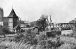 55 4934 auf Rangierfahrt am Hammersteinweg an der Gleiskreuzung zwischen der Bahnstrecke Biederitz–Magdeburg-Buckau (rechts von der Hubbrücke kommend) und dem Rangiergleis am Magdeburger Elbbahnhof. Links ist der Wasserturm der Hubbrücke Magdeburg zu sehen, dahinter der Magdeburger Dom. Der Wasserturm gehörte zum hydraulischen Antrieb der die Elbe überspannenden Hubbrücke. Das Mittelfeld dieser Eisenbahnbrücke war beweglich und wurde bei höheren Wasserständen oder Schiffsverkehr zeitweise hochgezogen. Das für den hierfür bestehenden hydraulischen Antrieb erforderliche Wasser wurde in dem Turm mit etwa 50 bis 70 at bereitgehalten. (07.1956) <i>Foto: Jürgen Hagemann</i>