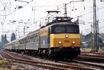 Die Baureihe 1100 der Nederlandse Spoorwegen (NS) war eine elektrische Universallok für 1,5 kV Gleichspannung mit der Achsfolge Bo’Bo’, die in den Jahren 1950 bis 1956 basierend auf der Reihe BB 8100 der Société nationale des chemins de fer français (SNCF) von Alsthom in 60 Exemplaren gebaut wurde. Nachdem bei mehreren Unfällen die Lokpersonale schwer verletzt oder getötet wurden, baute man zwischen 1978 und 1982 im Werk Tilburg alle 58 noch vorhandenen Fahrzeuge um. Sie erhielten dadurch ein neues, von markanten Vorbauten geprägtes Erscheinungsbild, um das Personal im Falle einer Kollision besser zu schützen. Die umgebaute NS 1113 fährt mit dem D 223 "Holland-Wien-Express" in Emmerich ein. (06.1982) <i>Foto: Ulrich Hesse</i>